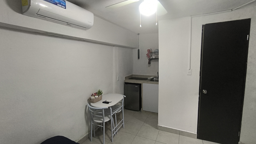 El Loft donde se ve la mesa, la codineta, el aire acondicionado y la puerta del baño